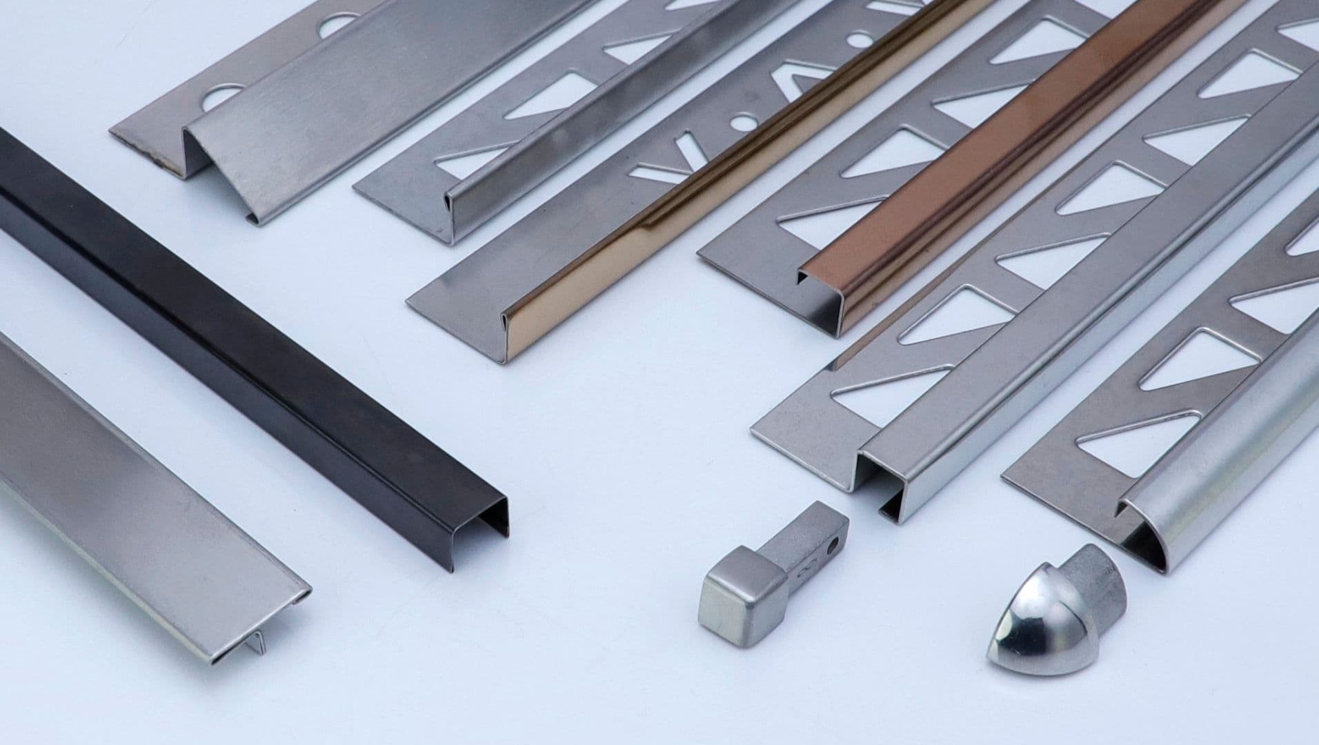 A collection of stainless steel tile trims on a neutral background