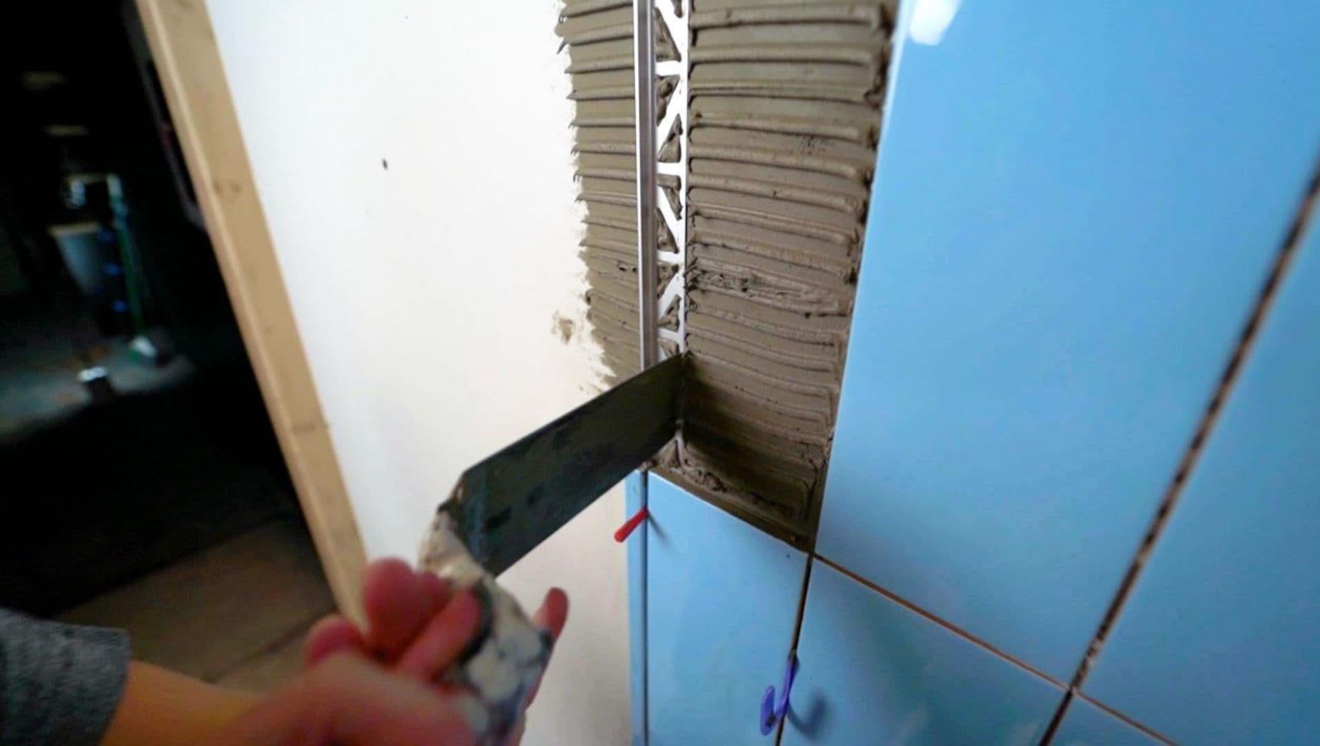 Close-up of a worker installing tile edge trim with precision