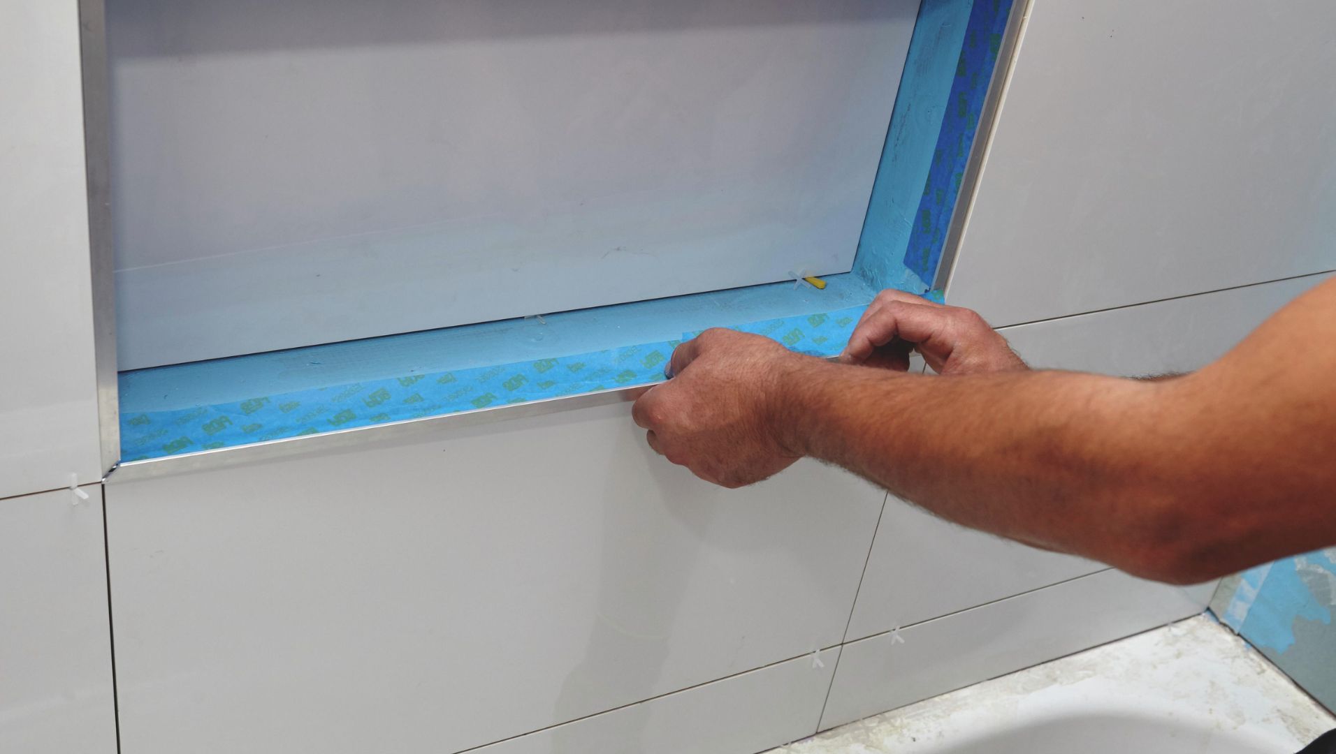 Close-up of aluminum tile trim installation on a wall