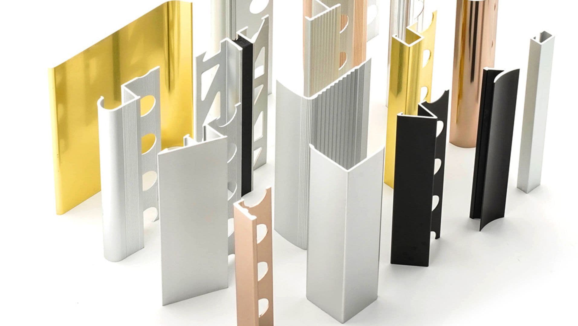 Various aluminum tile trims displayed on a wooden table.