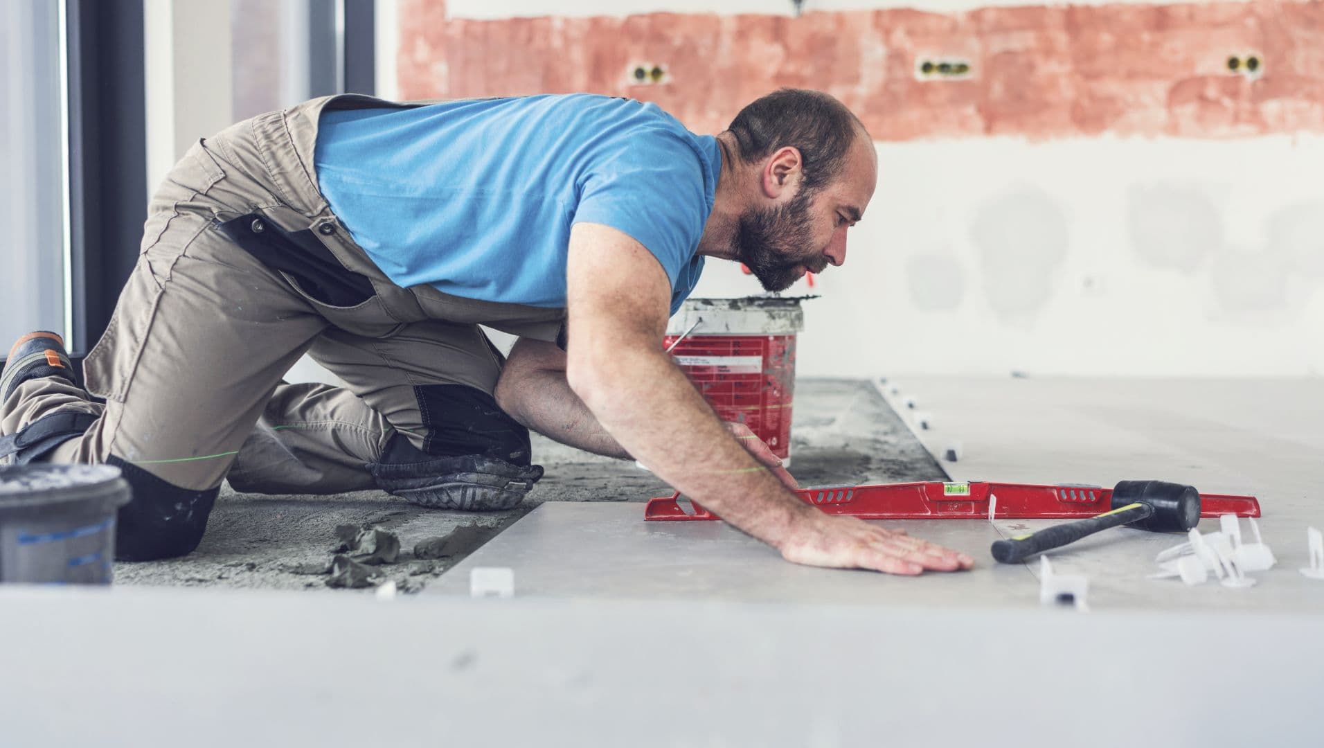 A person tiling a bathroom floor with precision tools and spacers