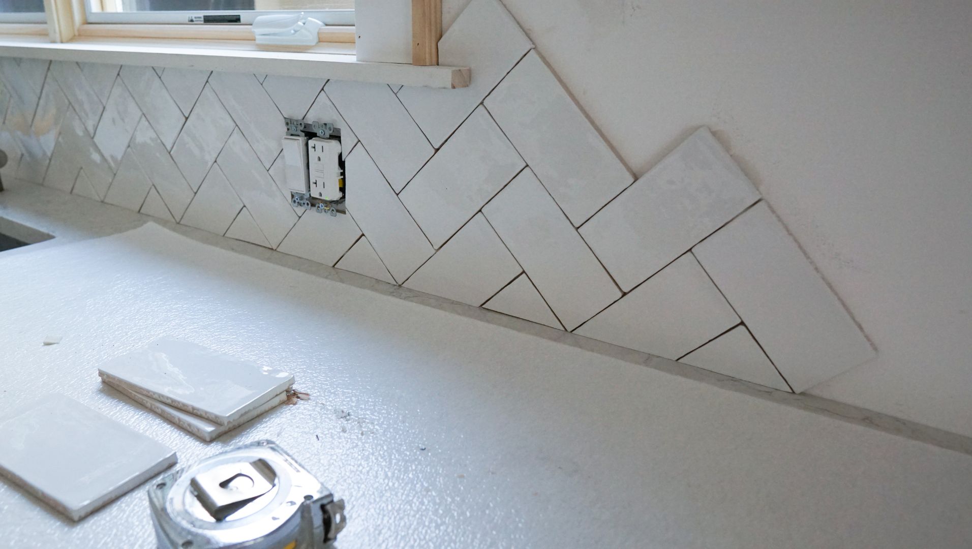 Hand applying tile trim to a completed tile wall