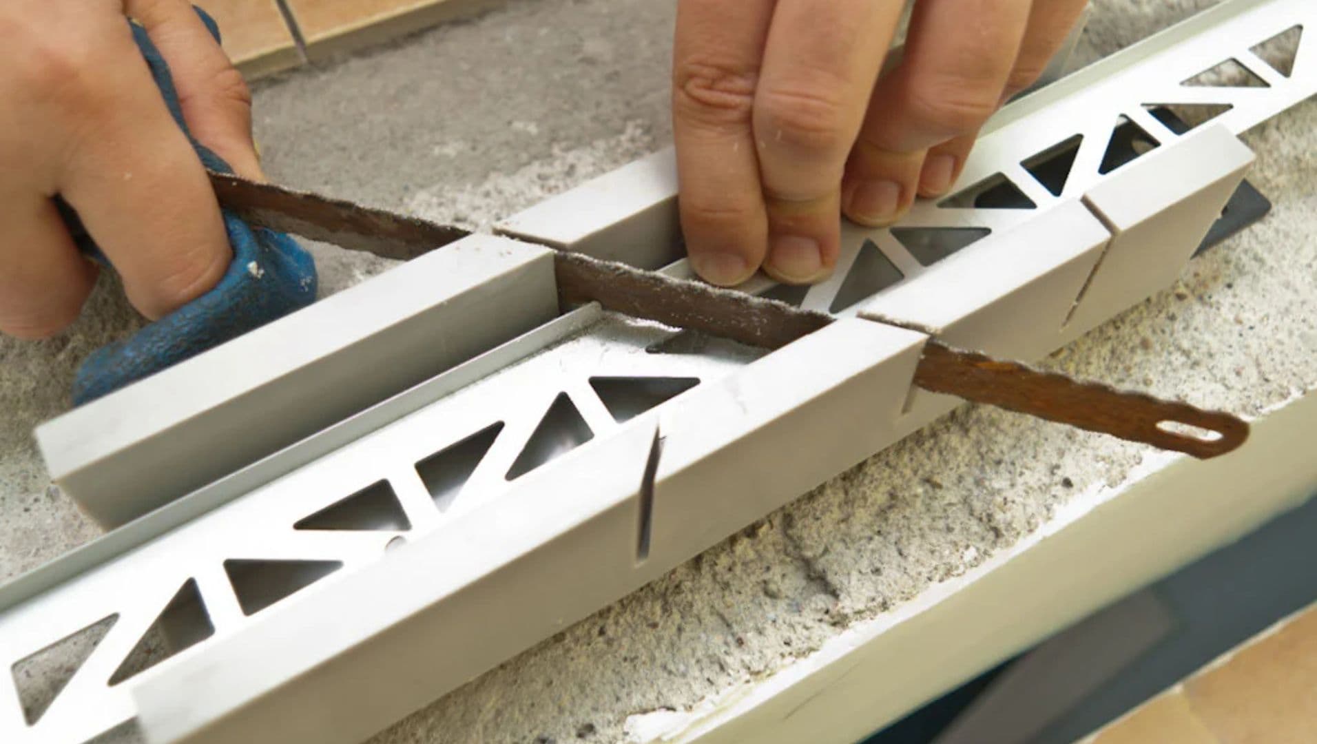 Person cutting metal tile trim with a miter saw on a workbench