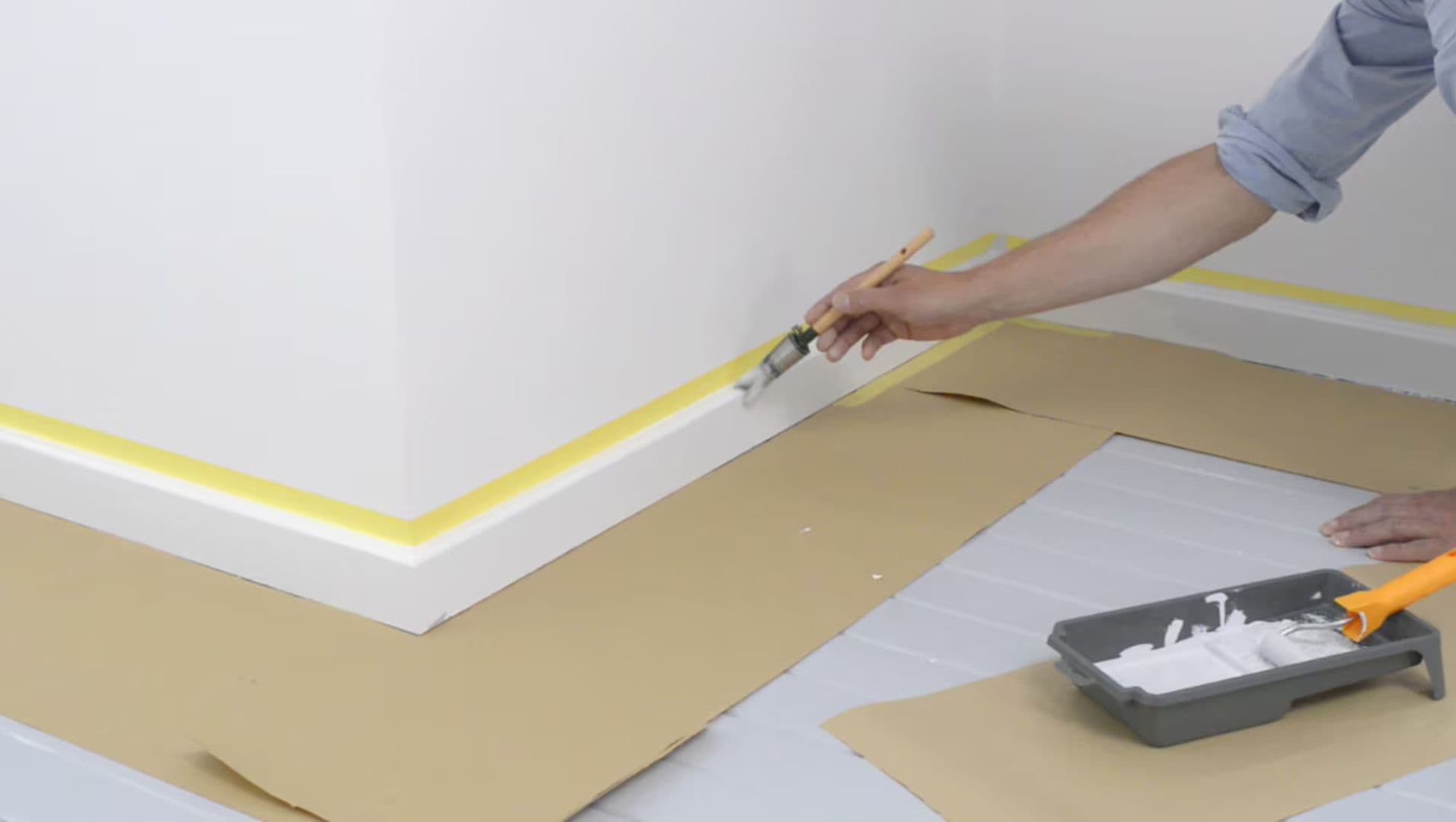Close-up of a person painting skirting boards with a brush
