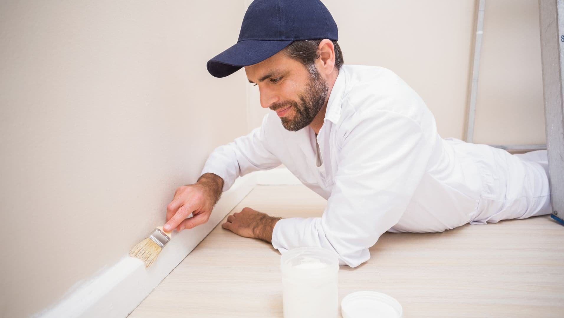 A person painting a skirting board in a modern living room