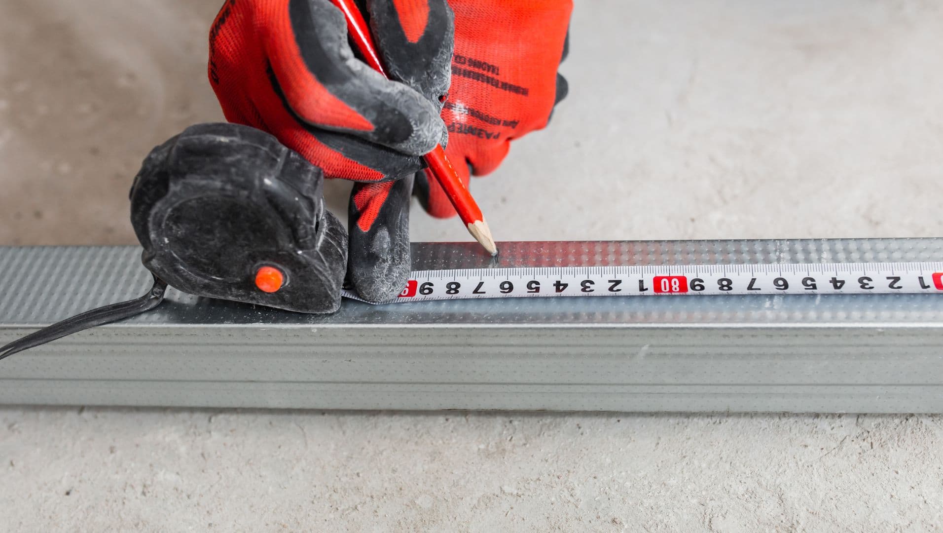 Close-up of a person measuring and cutting tile edge trim using precise tools