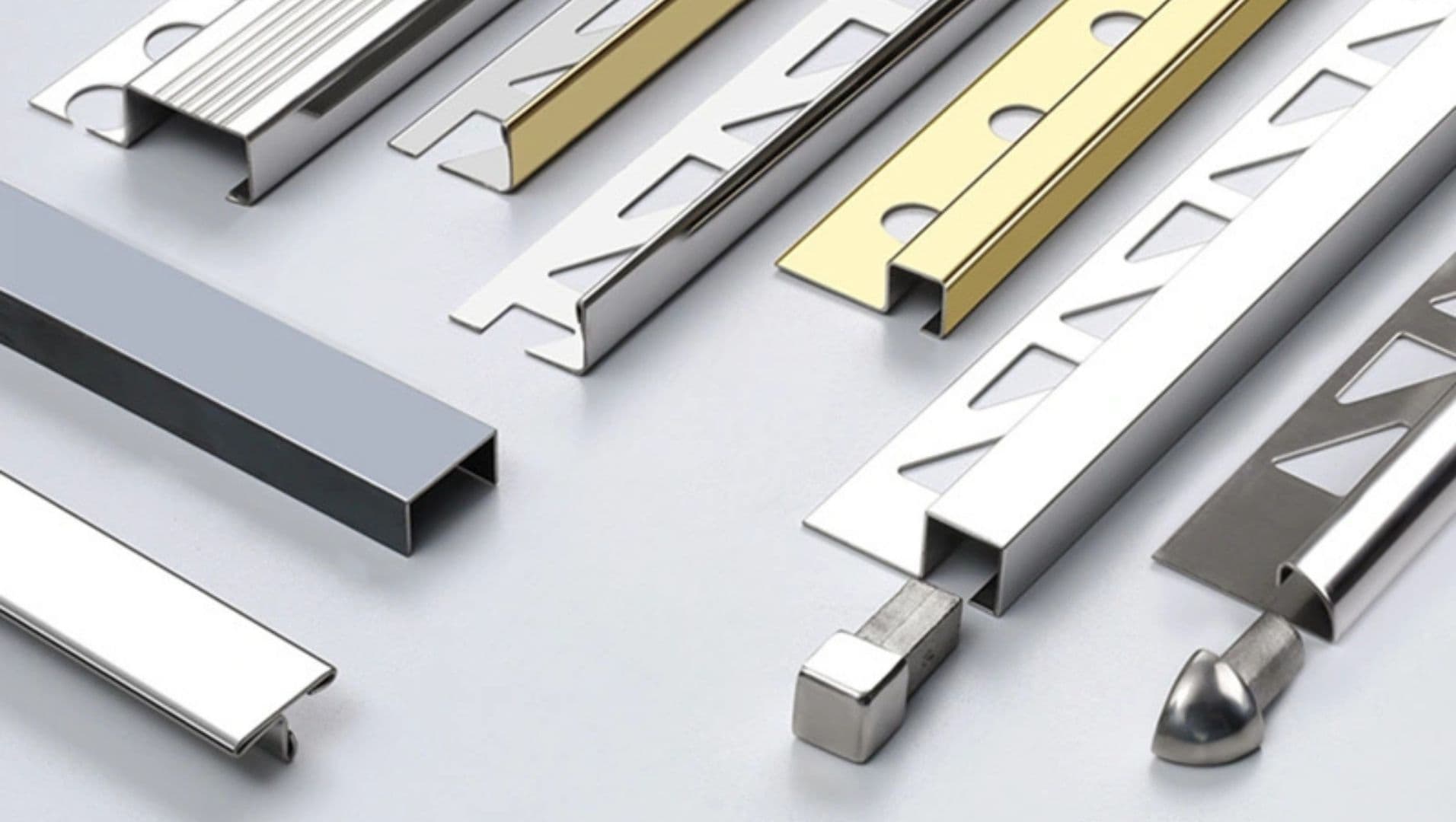 A collection of various stainless steel tile trims on a white surface