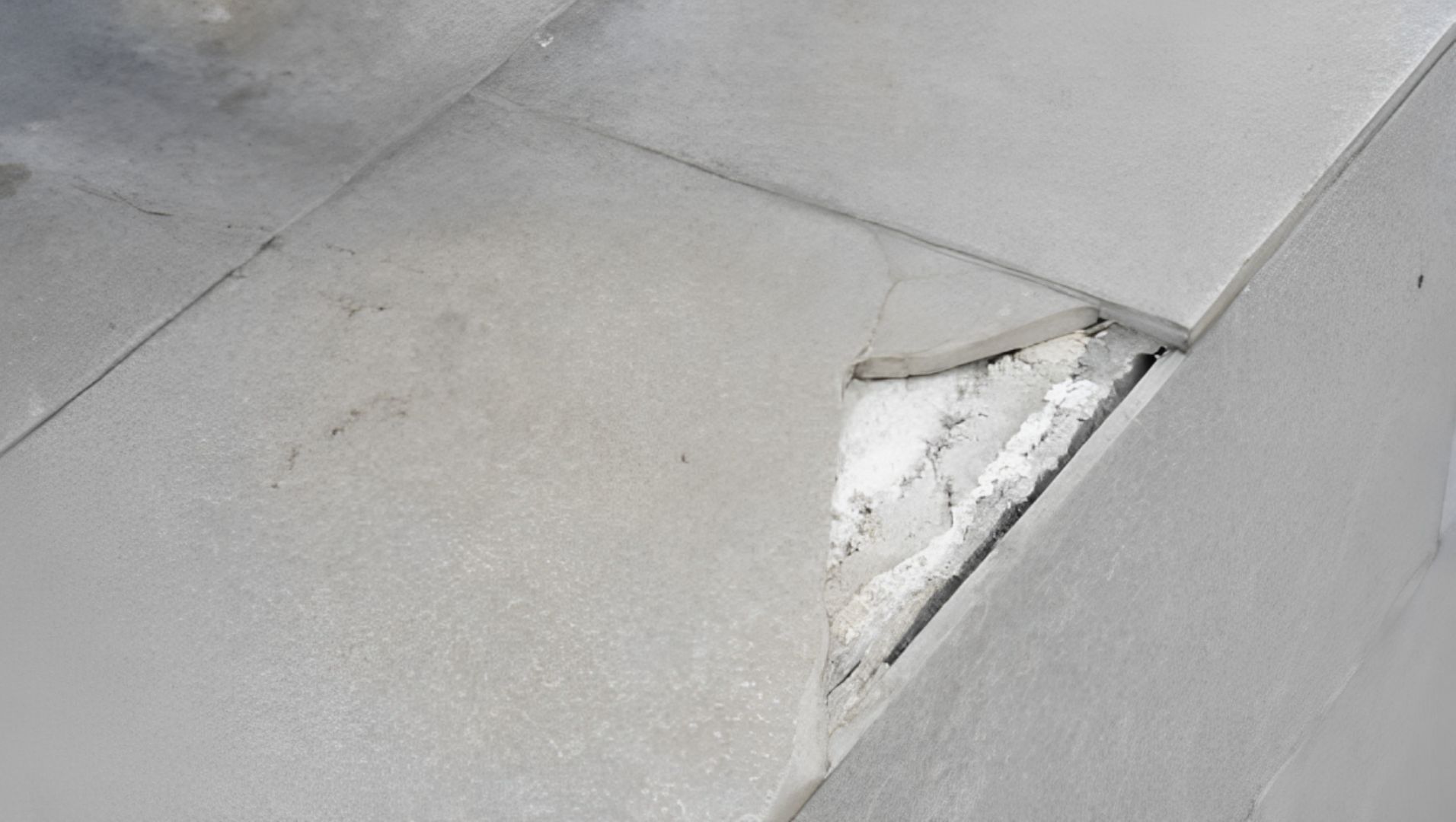 Exposed tile edges without trim, showing chips and uneven surfaces