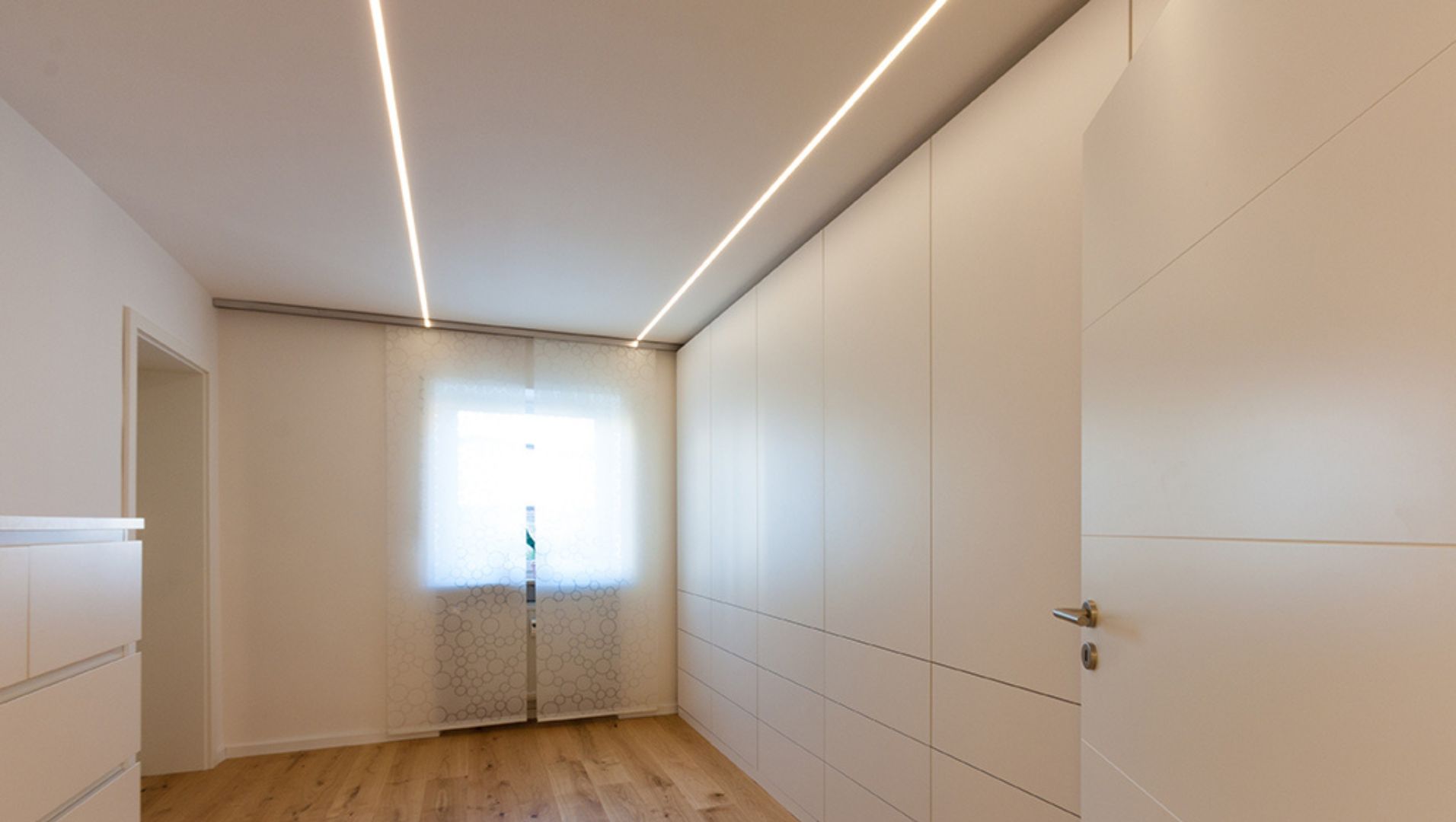 A close-up view of U-shaped LED lighting profiles installed on a modern ceiling.