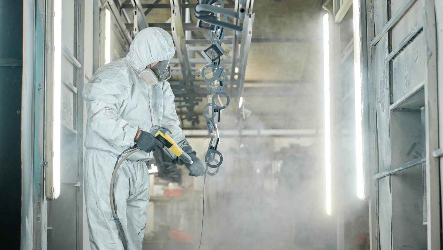 A professional powder coating workshop with equipment and safety gear.